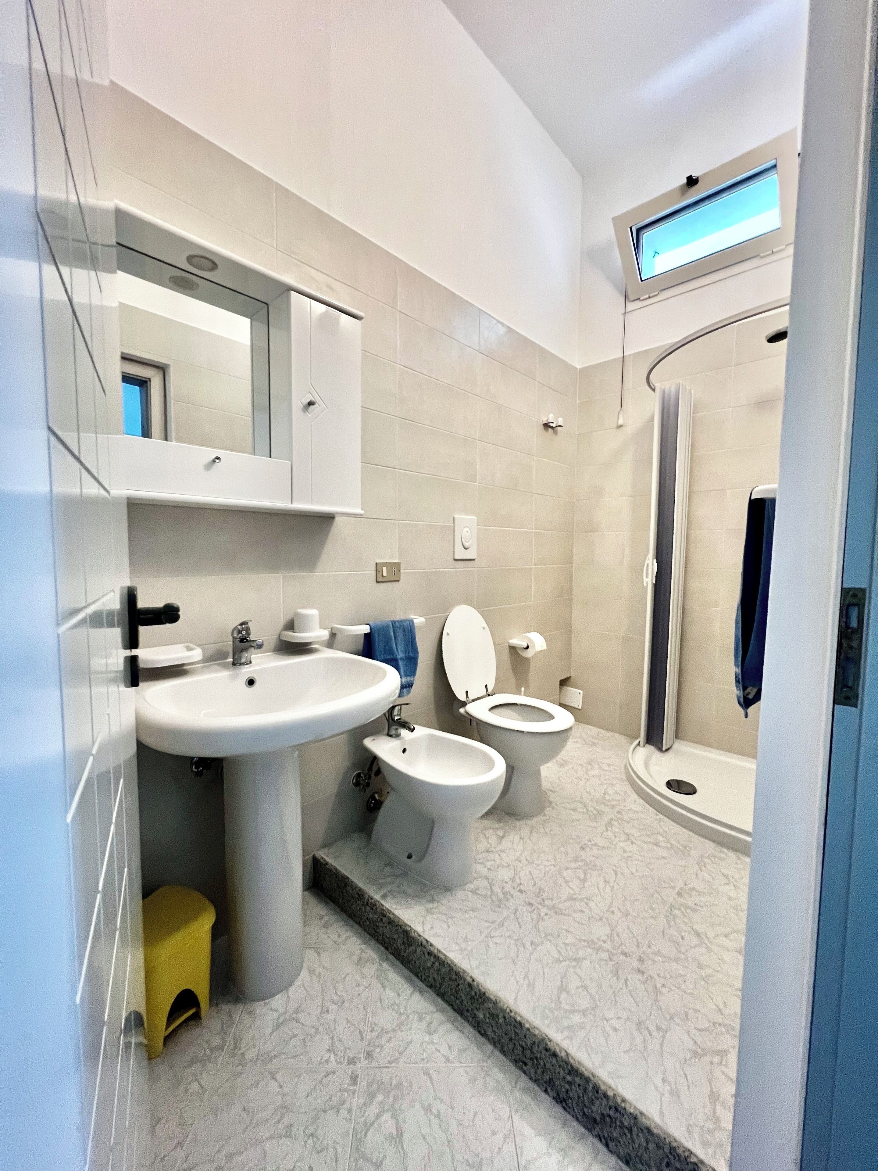 Un baño moderno con lavamanos, dos inodoros, un bidé y una ducha.
