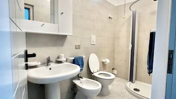Un baño moderno con lavamanos, dos inodoros, un bidé y una ducha.