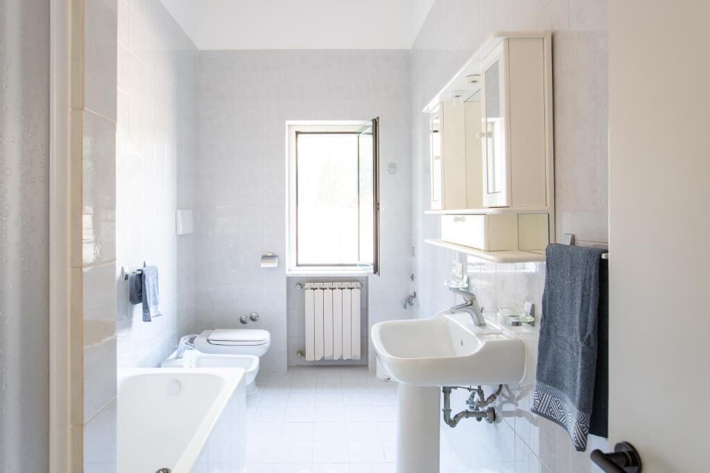 Une salle de bain moderne avec une baignoire, des toilettes, un lavabo et une fenêtre.