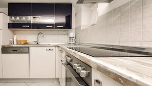Una cucina moderna con mobili bianchi, una cappa in acciaio inossidabile, un forno integrato e un ampio piano di lavoro.
