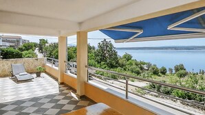 Un balcone con pavimento a scacchi, una poltrona relax e vista sul mare.