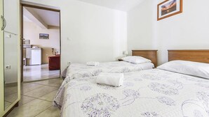 Una camera d'albergo con due letti, una testiera in legno, un comodino con una lampada e un quadro appeso al muro.