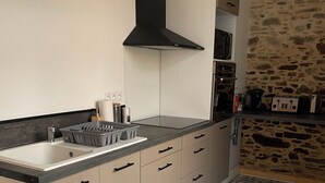 A modern kitchen with a sink, stove, and black range hood. - Apartment Le Pellerin (Le Pellerin)