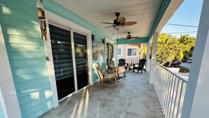 A covered porch with a tiled floor, a ceiling fan, and a seating area with chairs and a table. - Casa Brilliance Key Largo Retreat – Family-Friendly 3BR Island Getaway (Key Largo)