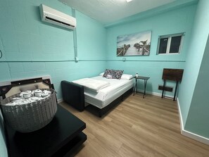 A room with a bed, a small table, a chair, an air conditioning unit, and a painting on the wall. - Casa Brilliance Key Largo Retreat – Family-Friendly 3BR Island Getaway (Key Largo)