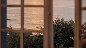 Blick durch ein fensterförmiges Raster auf ein Gewässer und eine entfernte Uferlinie mit Vegetation.