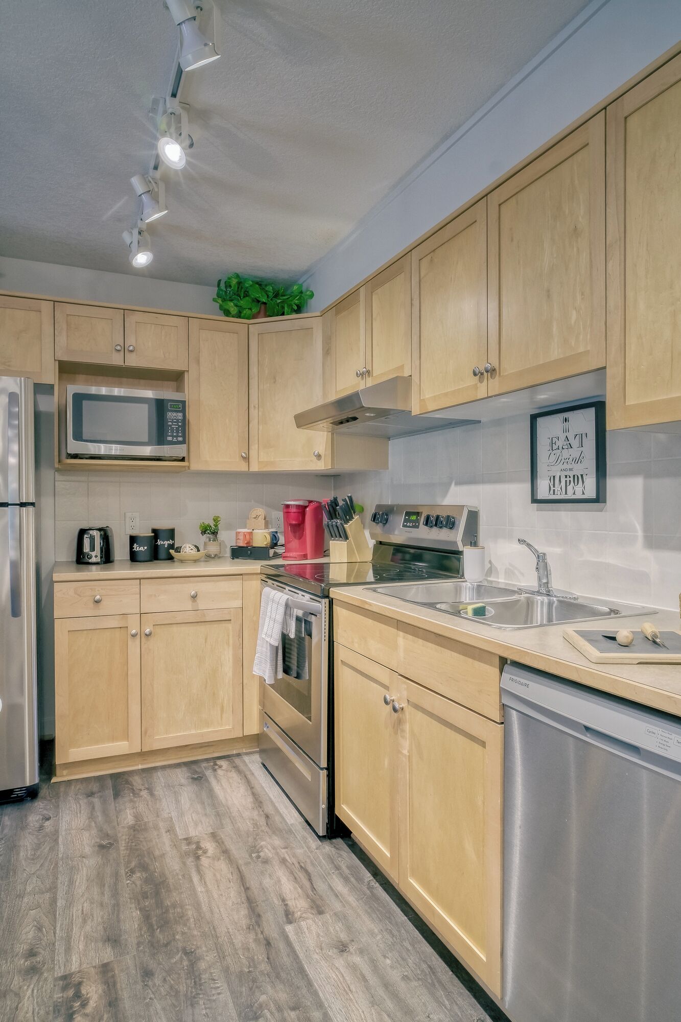 A modern kitchen with wooden cabinets, stainless steel appliances, and a tiled backsplash.