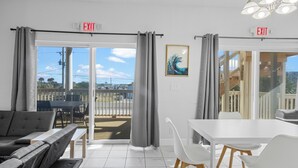 Une pièce moderne comprenant un coin repas, deux rideaux gris, une table blanche et une vue sur l’extérieur.