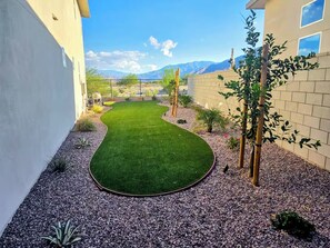 A landscaped garden with a curved lawn, gravel paths, and various plants. - Luxe Desert Escape on the Grove w/ 360° Mountain Views (Palm Springs)