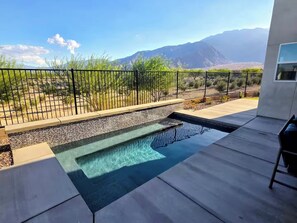 A swimming pool with a view of mountains, surrounded by a black fence and a patio area. - Luxe Desert Escape on the Grove w/ 360° Mountain Views (Palm Springs)