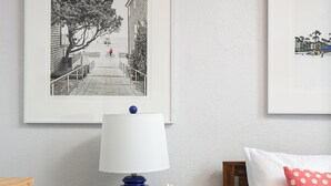 Ein ordentlich eingerichtetes Schlafzimmer mit einem Bett, einem Nachttisch mit Lampe, einem gerahmten Bild an der Wand und einer kleinen Dekorationsvase.