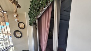 A balcony with wicker chairs, a small table with a book and a cup, and a view of the interior through a curtain. - Elegant & Comfortable Apartment with Private Balcony (Santo Domingo Este)