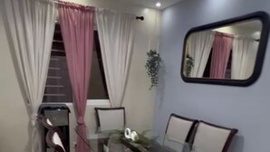 A dining area with a glass table surrounded by chairs, a staircase with curtains, and a mirror on the wall. - Elegant & Comfortable Apartment with Private Balcony (Santo Domingo Este)