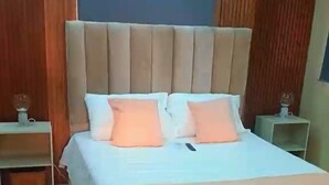 A bedroom with a large bed, wooden headboard, two bedside tables, and a nightstand. - Elegant & Comfortable Apartment with Private Balcony (Santo Domingo Este)