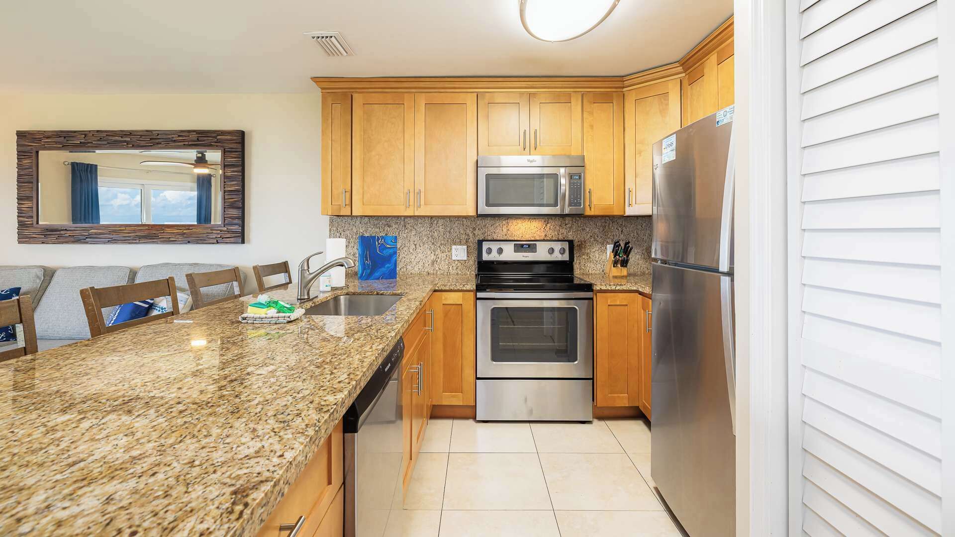 A kitchen with granite countertops, stainless steel appliances, wooden cabinets, and a large window.