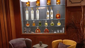 A bar area with two armchairs, a small table, and a display of liquor bottles. - Hotel Sternen Gurtnellen (Gurtnellen)