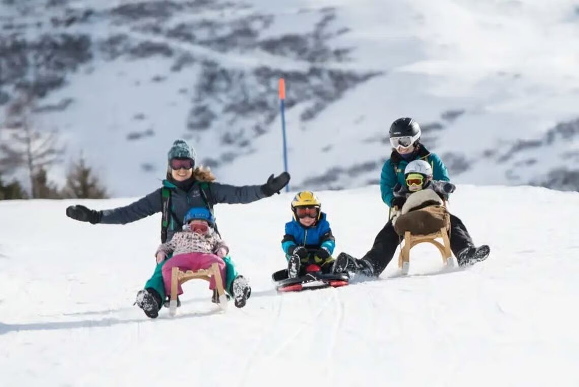 Un grupo de personas deslizándose por una pendiente nevada.