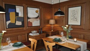 A dining area with wooden paneling, abstract art on the walls, a table set with green plates, and a lamp. - Hotel Sternen Gurtnellen (Gurtnellen)