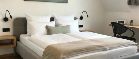 A modern bedroom with a bed, bedside tables, a desk, and a chair.