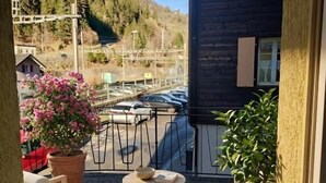 A balcony with two chairs and a table, overlooking a parking area and a building with a dark facade. - Hotel Sternen Gurtnellen (Gurtnellen)