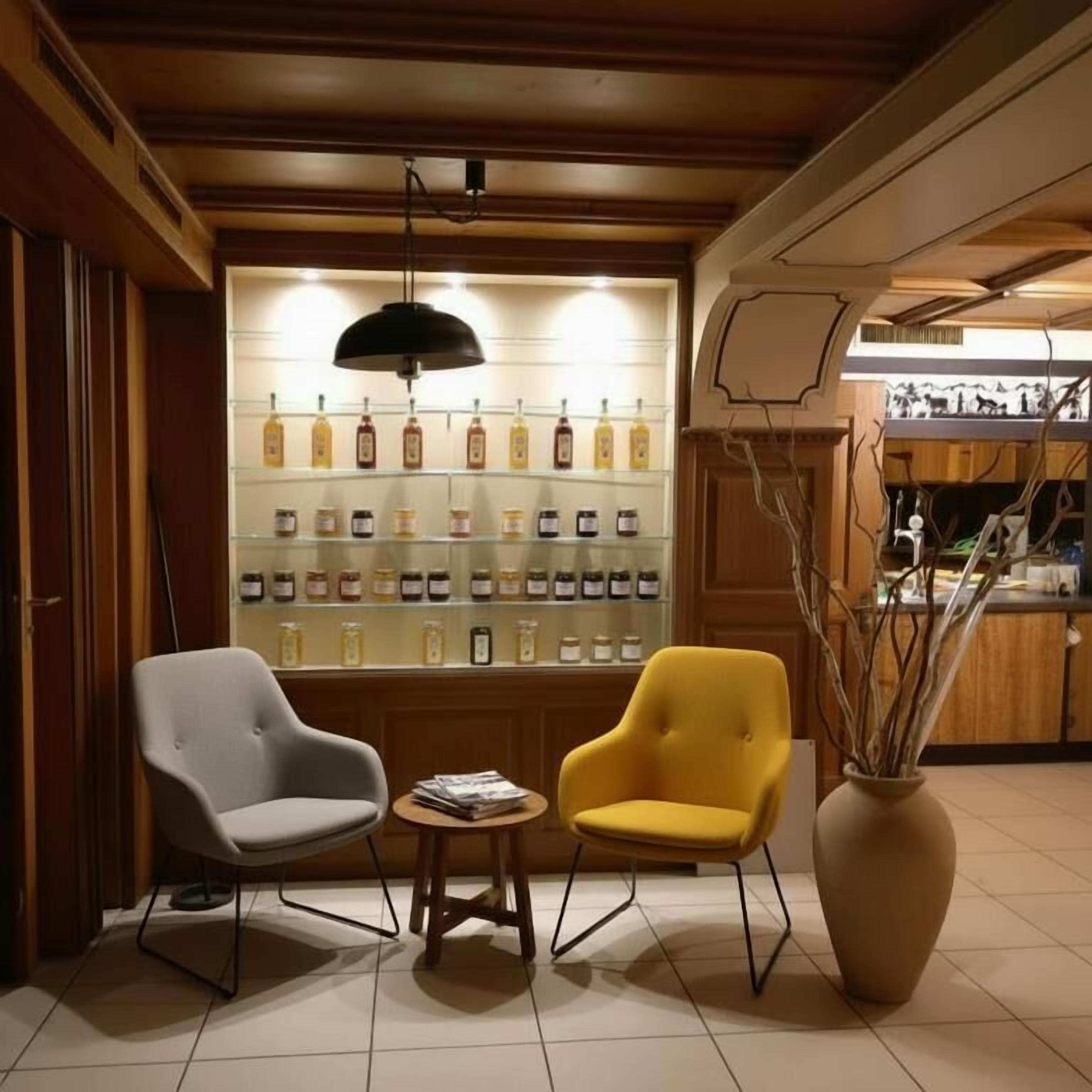 Un área de estar con dos sillas, una mesita y una pared que exhibe varias botellas.