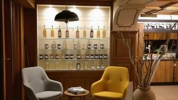 Un área de estar con dos sillas, una mesita y una pared que exhibe varias botellas.