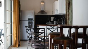 Et moderne køkken med køleskab, komfur og spiseplads med stole og bord.