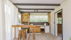 A kitchen with a brick wall, wooden stools, a wooden table, and a window with curtains.