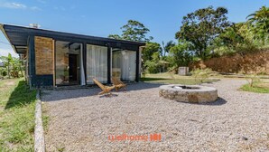 A modern house with a gravel driveway, a fire pit, and a wooden chair.