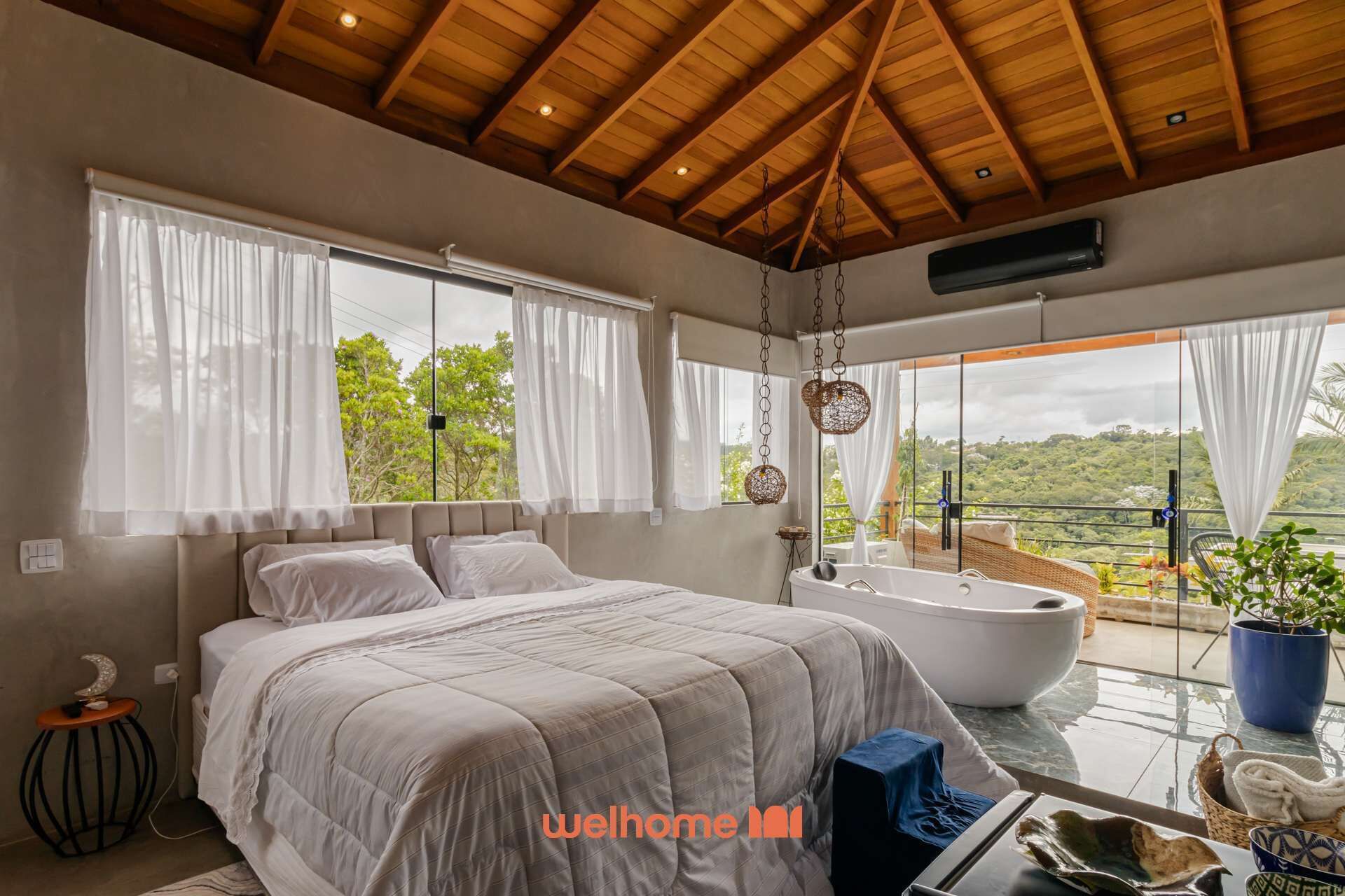 A bedroom with a large bed, a bathtub, and a balcony with a view.