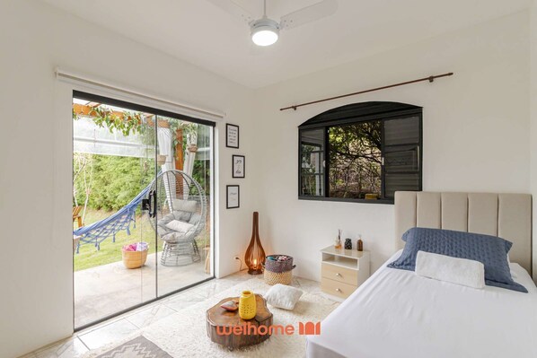 A bedroom with a bed, a window, a hanging chair, and a view of the outdoors. - Sitio em Ibiuna com piscina próximo rota do vinho (ibiuna)