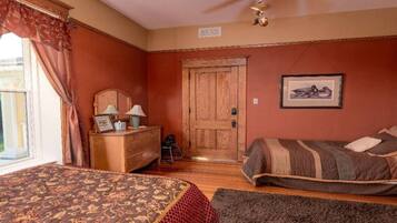 A bedroom with two beds, a wooden dresser, a chair, and a door.
