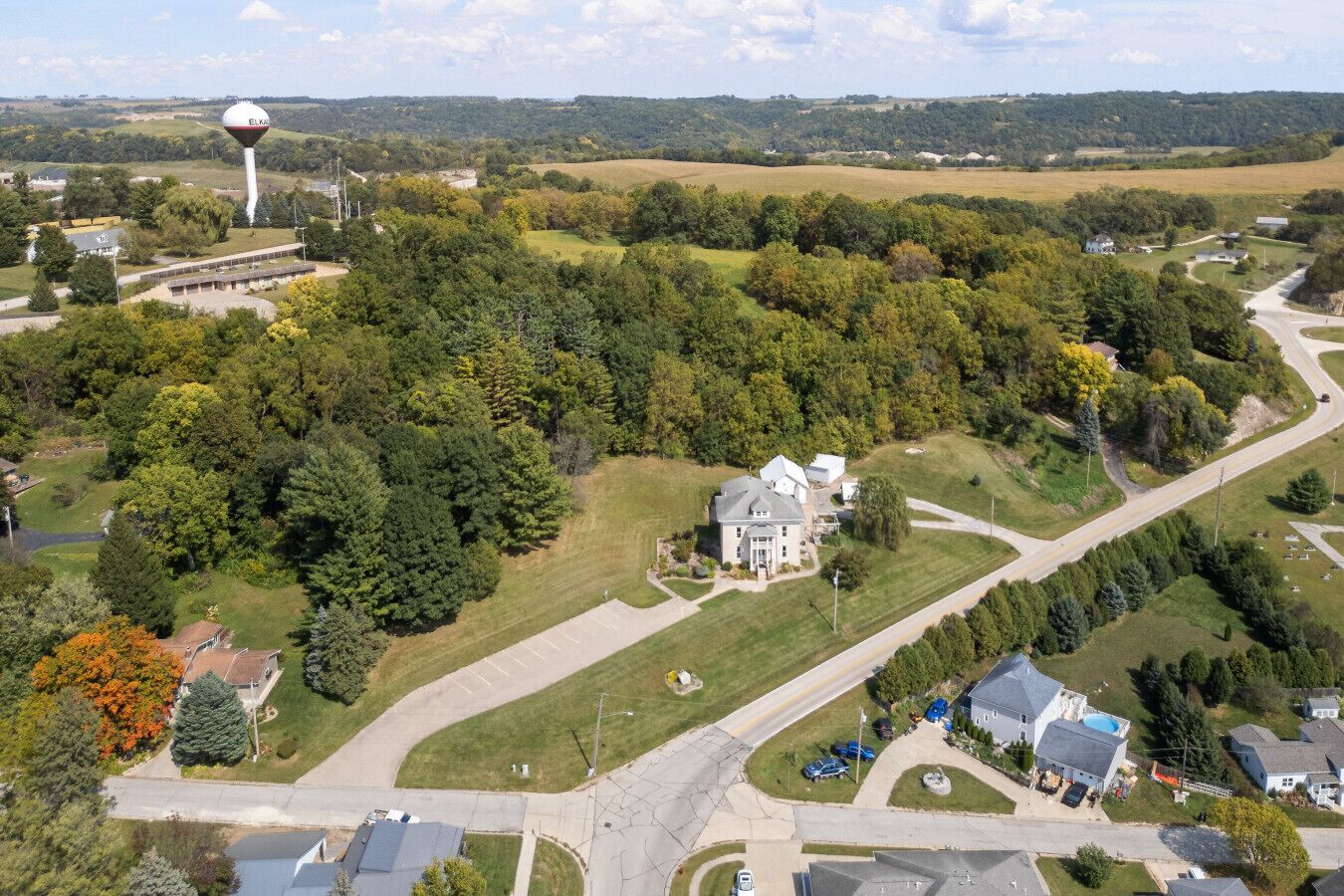 An aerial view of a residential area with a large house, a water tower, and a winding road.