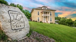 A stone with "Elkader Jail Inn" and "EST. 2008" engraved, a two-story house with a porch, and a grassy lawn.
