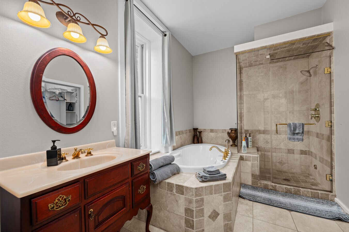 Ein Badezimmer mit Waschtisch, großem Spiegel, Badewanne und Dusche.