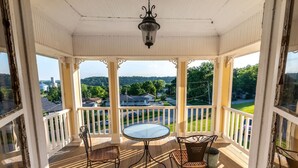 A covered porch with a table and chairs, overlooking a residential area.