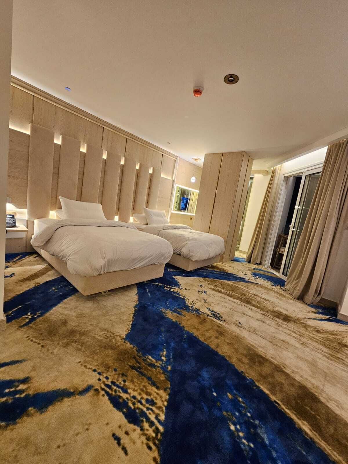Une chambre d’hôtel moderne dotée d’un grand lit, d’un canapé séparé, d’une grande fenêtre et offrant une vue sur la ville.