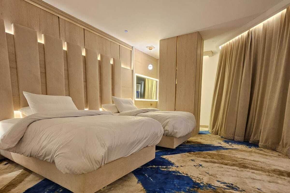 Una habitación de hotel moderna con una cama grande, un espejo y una alfombra estampada.
