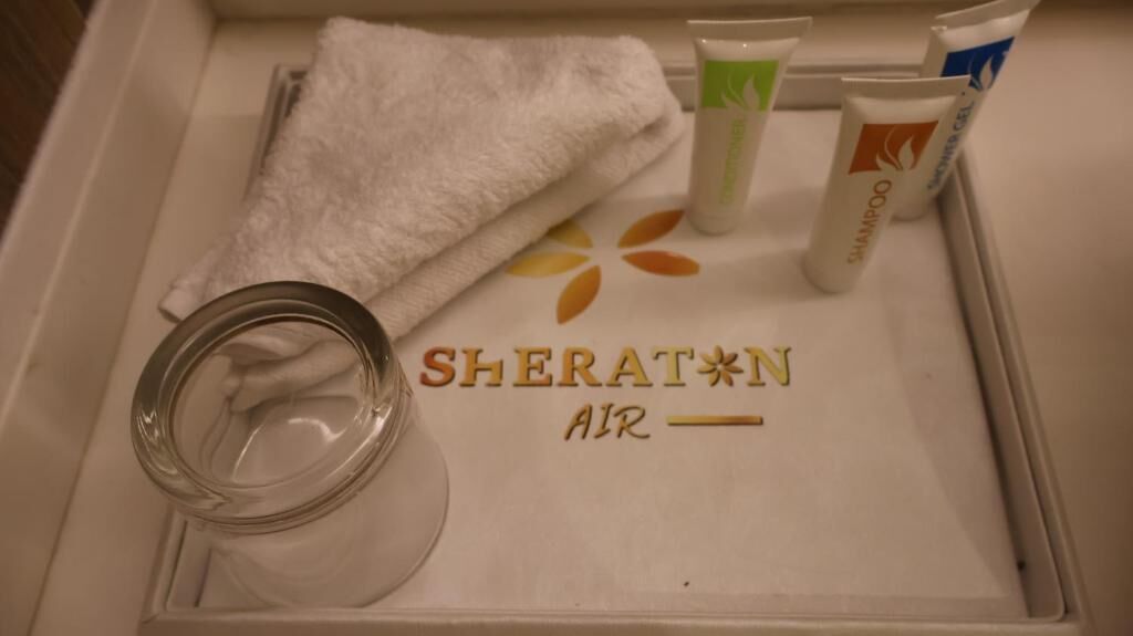 A bathroom vanity with toiletries, a towel, and a glass container.