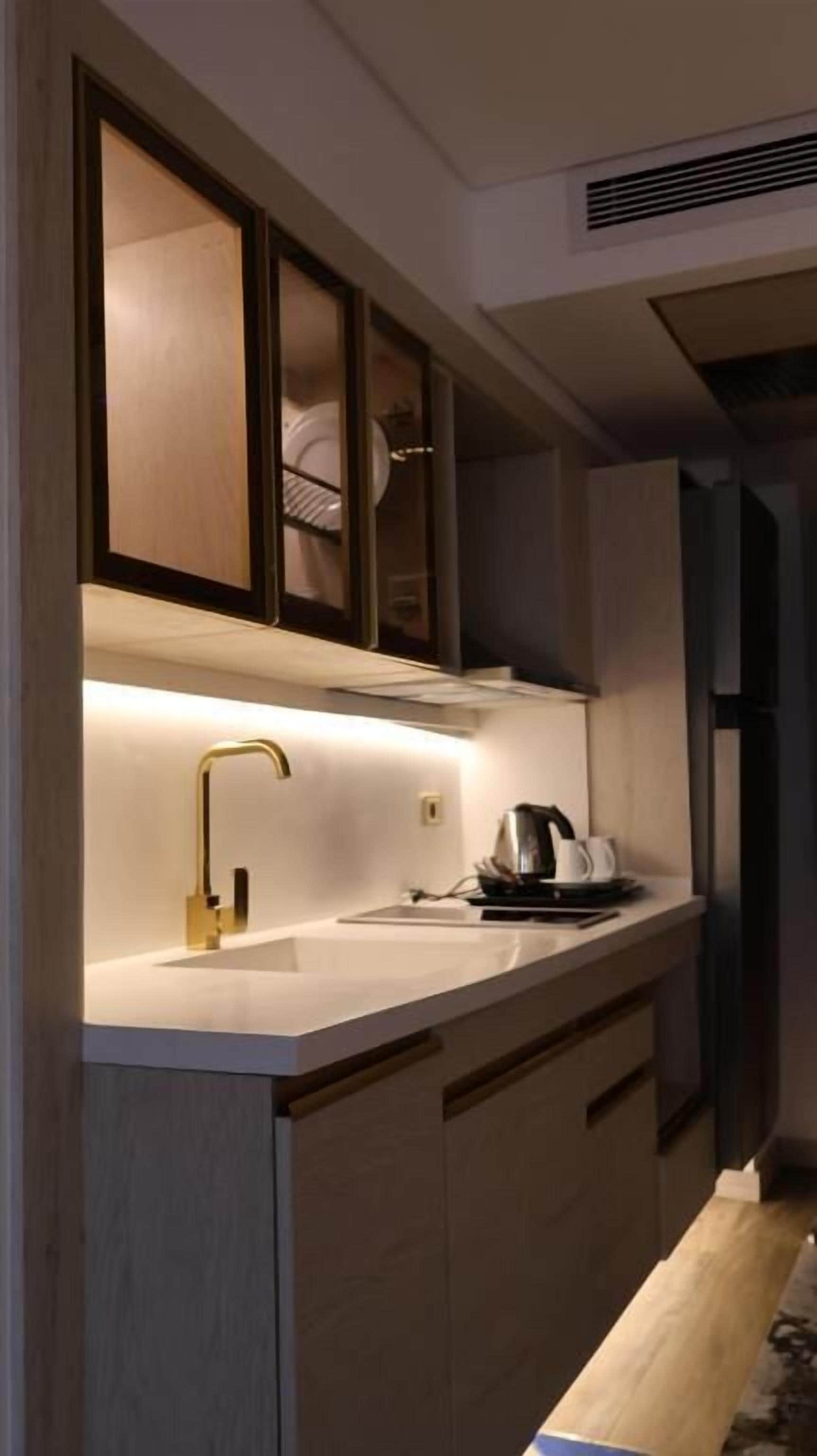A modern kitchen with a built-in oven, a coffee maker, and a sink with a gold faucet.