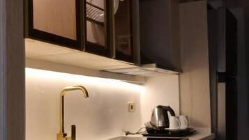 A modern kitchen with a built-in oven, a coffee maker, and a sink with a gold faucet.