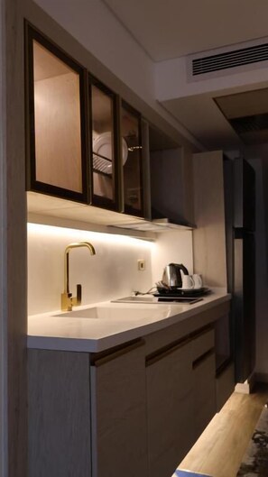Una cocina moderna con horno empotrado, cafetera y lavabo con grifo dorado.