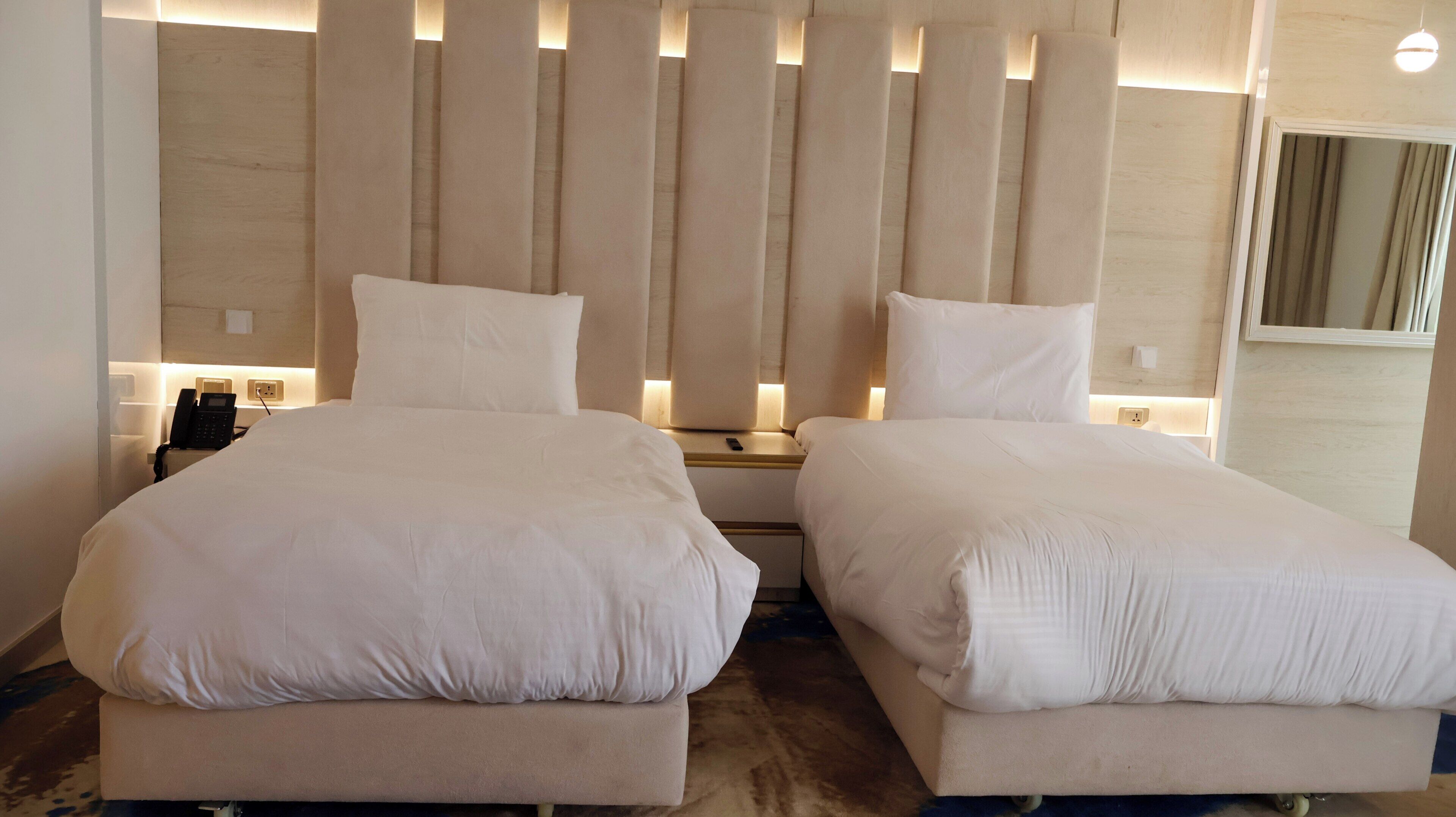Un lit double avec une tête de lit en bois, des tables de chevet avec des lampes et un téléphone.
