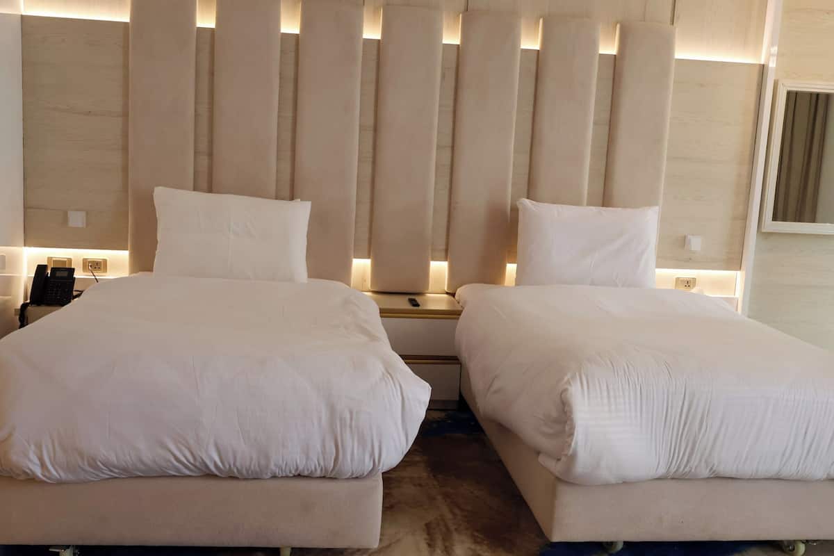 Un lit double avec une tête de lit en bois, des tables de chevet avec des lampes et un téléphone.