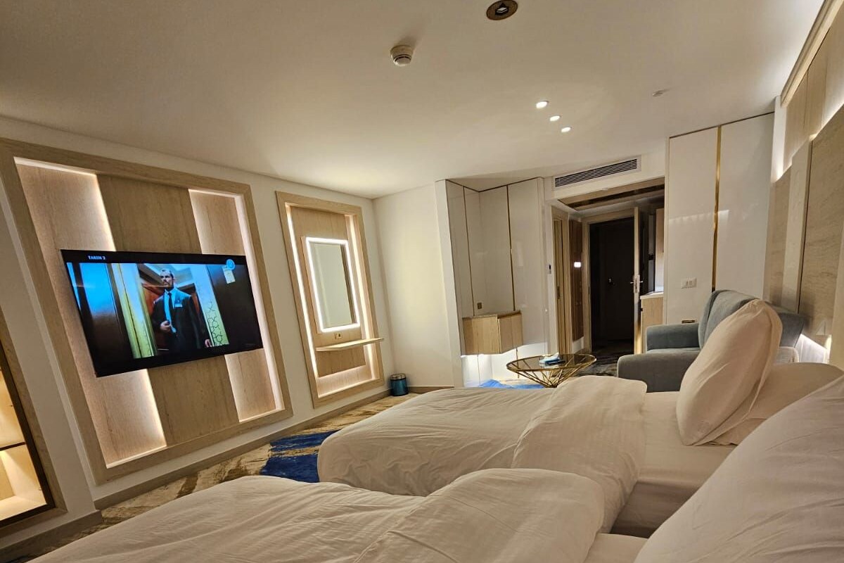 A modern hotel room with a large bed, a television, and a wardrobe.