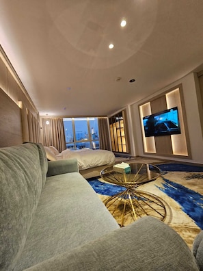 Un salon moderne avec un grand canapé, une table basse en verre et un téléviseur à écran plat fixé au mur.
