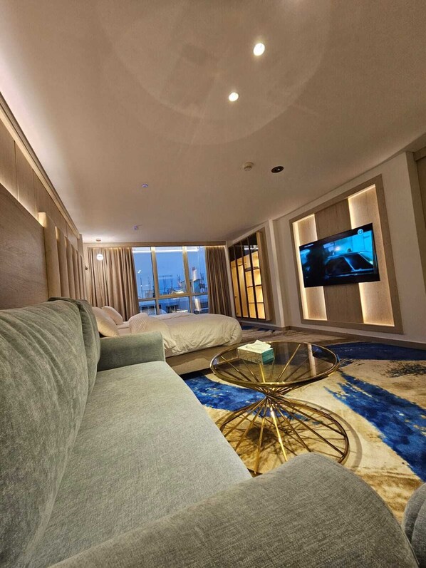 Una sala moderna con un sofá grande, una mesa de centro de vidrio y un televisor de pantalla plana montado en la pared.