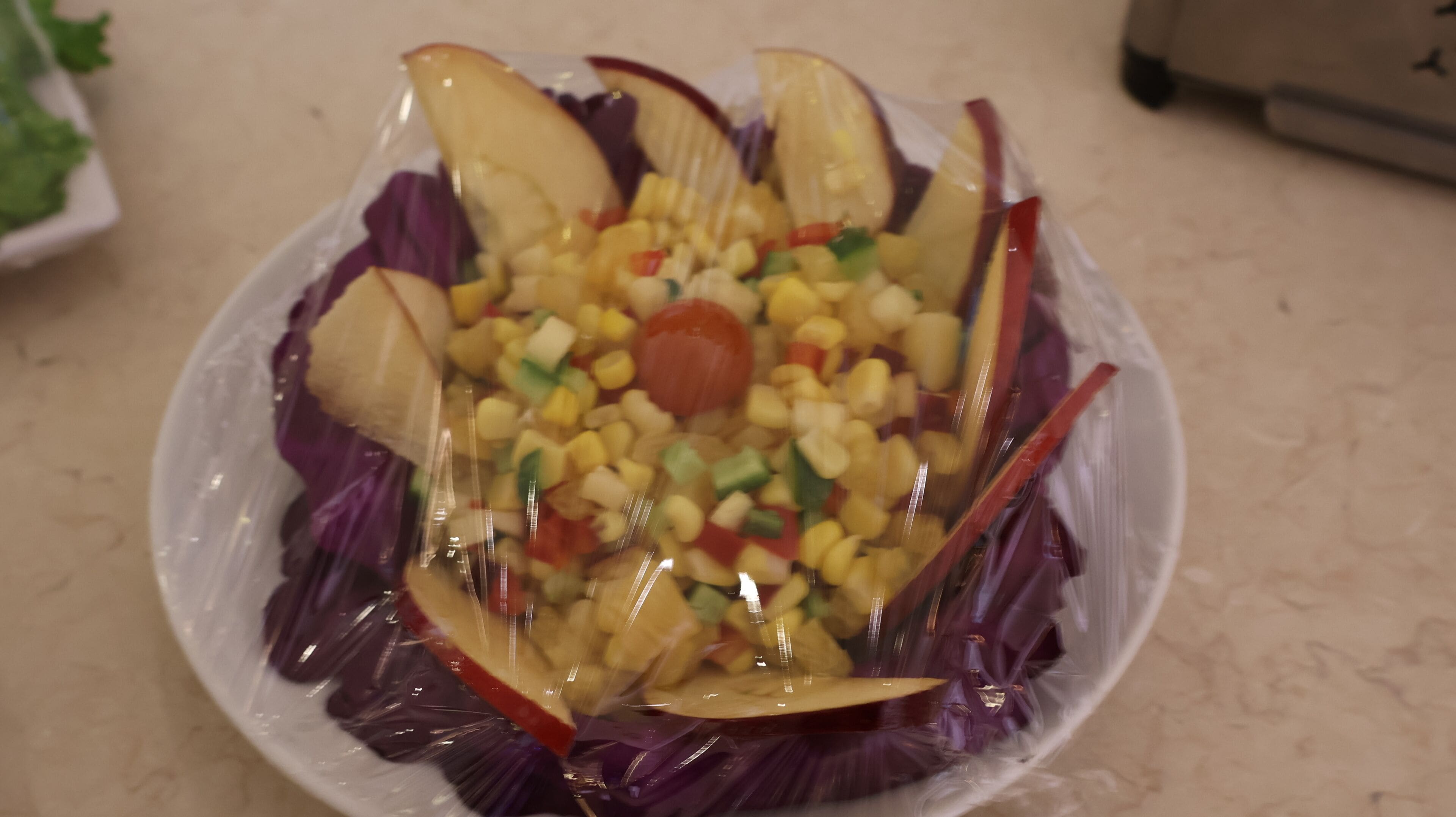 A salad with various vegetables and corn, served on a plate.