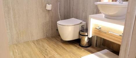 A bathroom with a toilet, sink, and a trash bin.