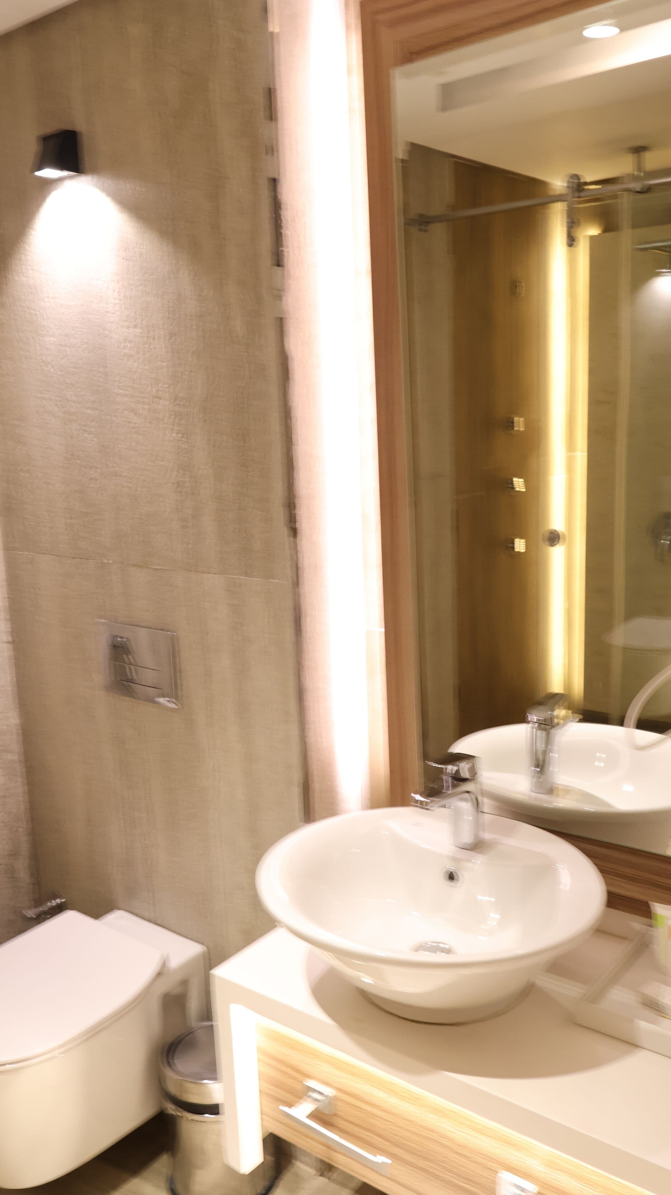 Une salle de bain avec un lavabo blanc, un miroir et des toilettes.
